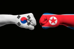 Dois punhos cerrados, pintados, um com a bandeira da Coreia do Sul e o outro com a bandeira da Coreia do Norte